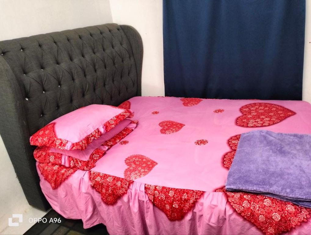 ein Bett mit einer rosa Tagesdecke mit Herz drauf in der Unterkunft Homestay Saujana Harmoni D'Petron in Gua Musang