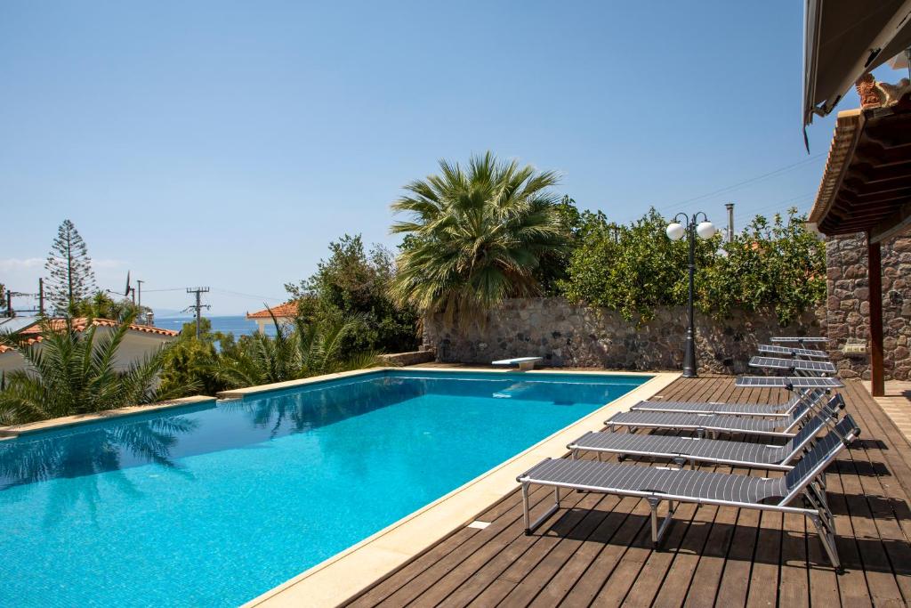 a swimming pool with lounge chairs next to a house at Green Villa Aegina in Aegenitissa