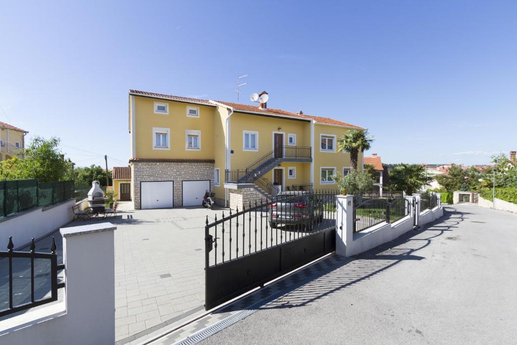 a large yellow house with a black fence at Apartments Euphemia in Rovinj