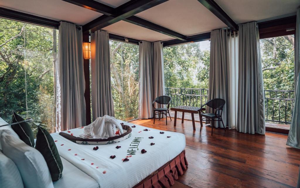 1 dormitorio con 1 cama en una habitación con ventanas grandes en Arangala Forest Lodge en Naula