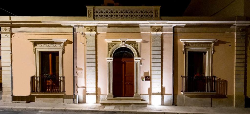 a white building with a brown door at night at Dimore Anna Maria -Casa Liberty- in Avola