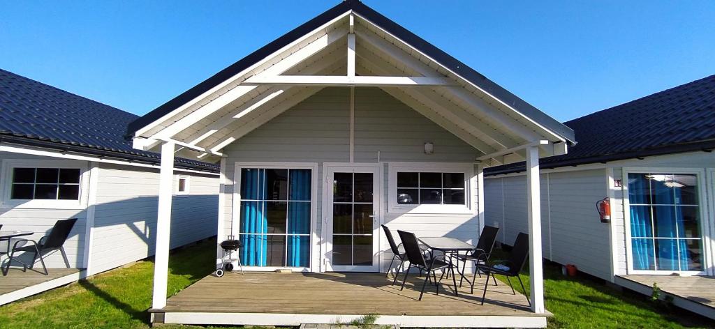 Cette maison blanche dispose d'une terrasse couverte avec des chaises et une table. dans l'établissement Domki Martes Wicie, à Wicie