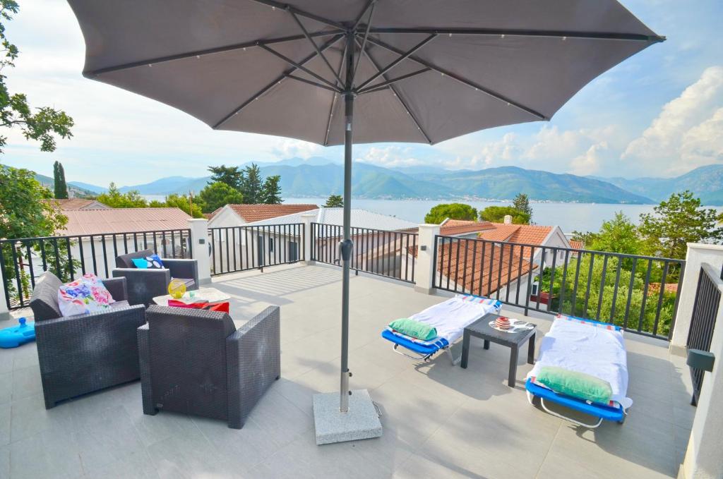 a patio with an umbrella and chairs and a table at Sun Ray Apartments in Tivat