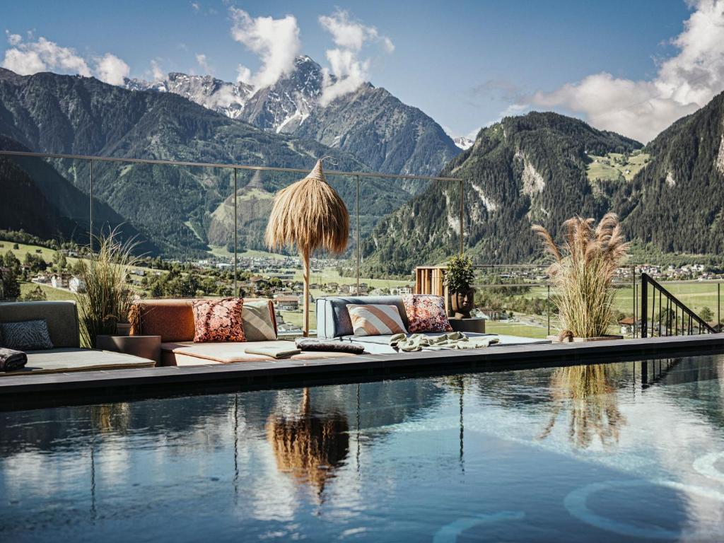 un complexe avec une piscine avec des montagnes en arrière-plan dans l'établissement Coolnest, à Mayrhofen