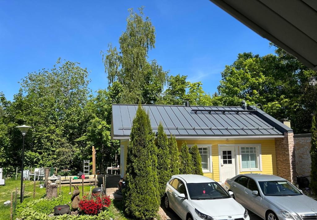 zwei Autos, die vor einem gelben Haus geparkt sind in der Unterkunft Villa Tourula in Jyväskylä