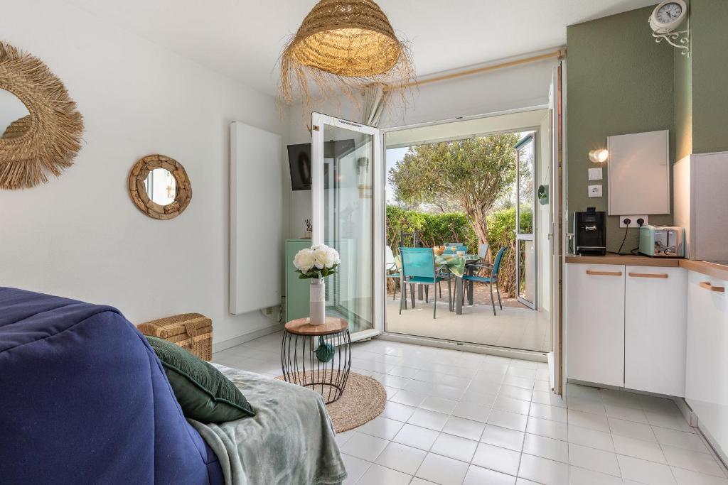 un salon avec un canapé bleu et une cuisine dans l'établissement The Bohemia by POM, terrasse, parking, au Cap d'Agde