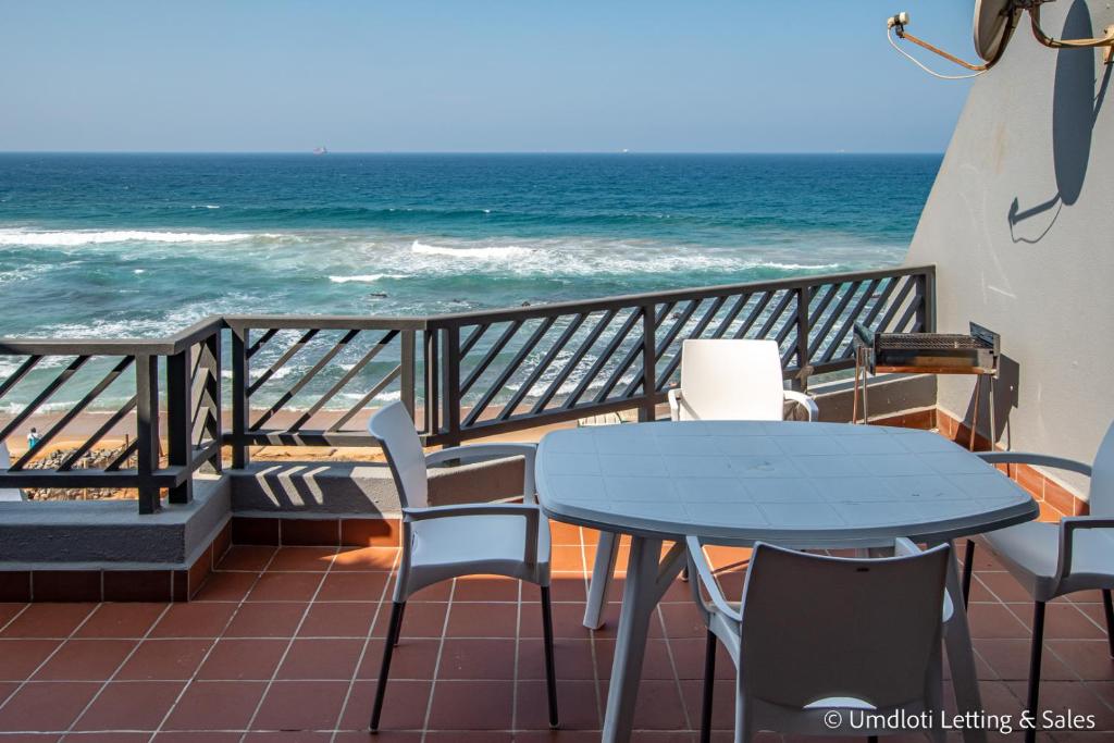 a table and chairs on a balcony with the ocean at Isikulu 27B in Umdloti