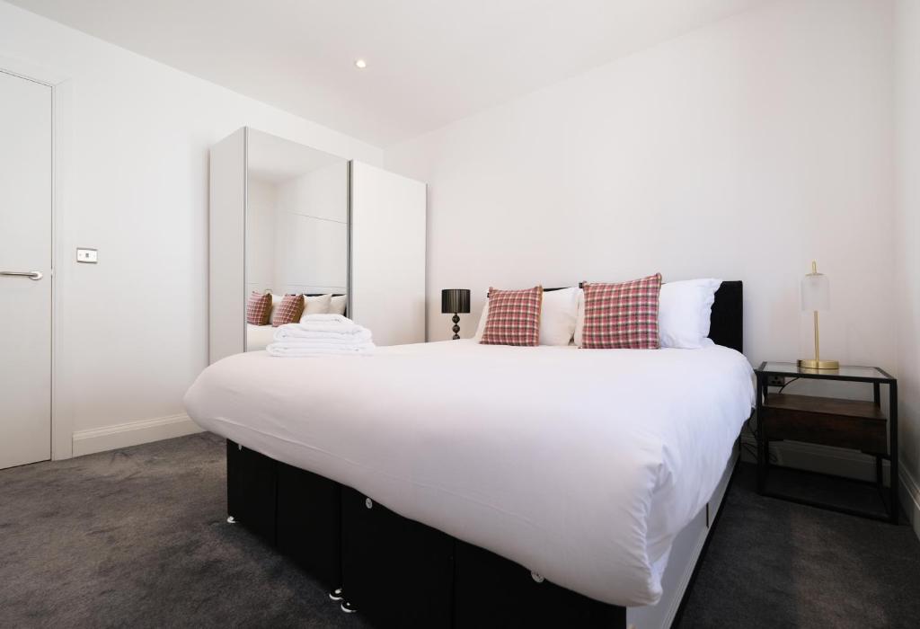 ein großes weißes Bett in einem Zimmer mit Spiegel in der Unterkunft Ealing Common Apartment with Balcony in London