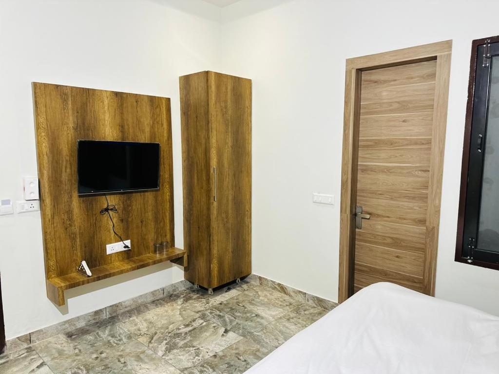 HOTEL SKYZ في Sirsa: غرفة نوم بسرير وتلفزيون على جدار