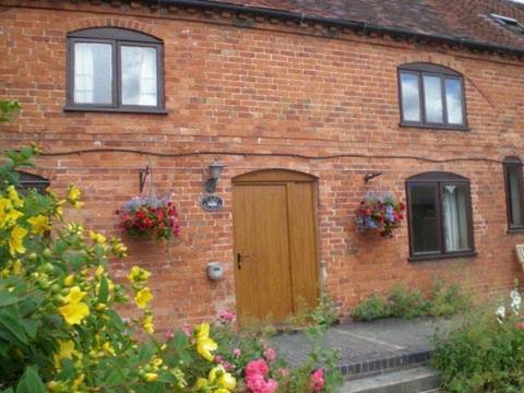 a brick house with a wooden door and windows at Irelands Farm Cottages in Birmingham