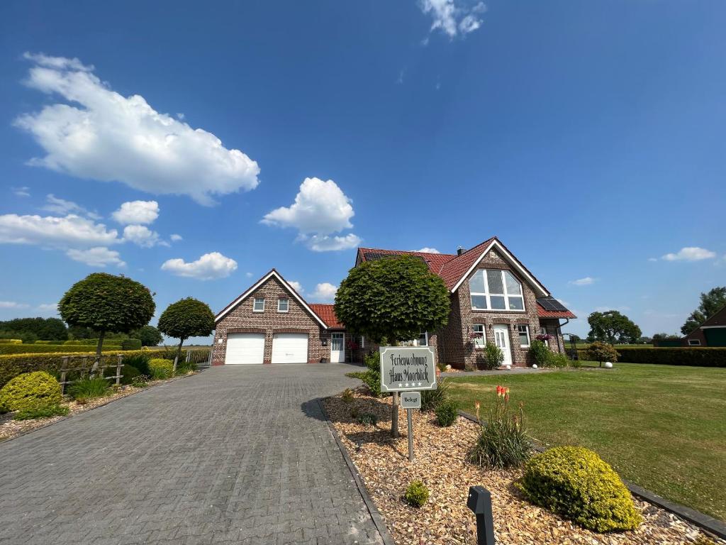 une maison avec un panneau en face d'une allée dans l'établissement Ferienwohnung Haus Moorblick Wiesmoor Ostfriesland mit Garten, à Wiesmoor