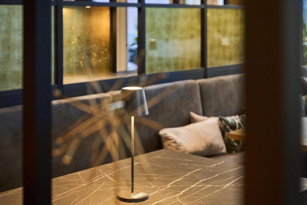 a table with a lamp in front of a couch at Hotel Rhönkitz in Bad Kissingen