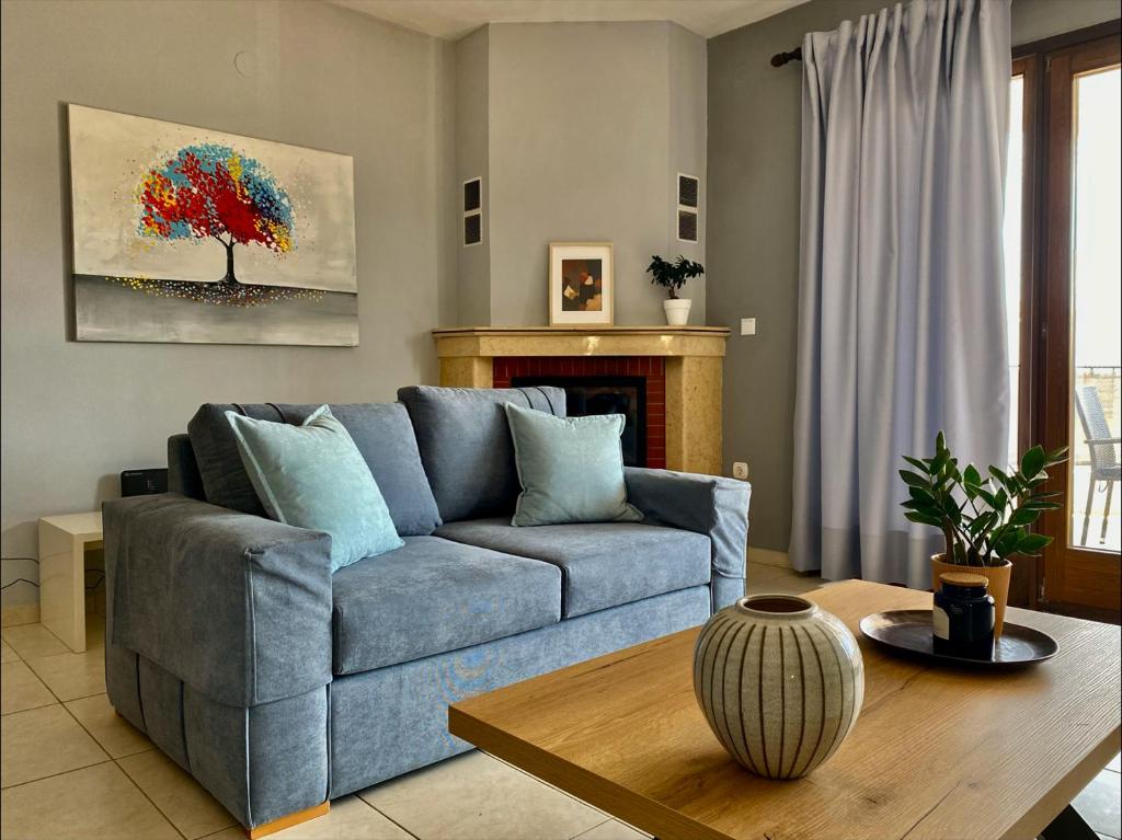 a living room with a blue couch and a table at Anemos Apartment in Keramotí