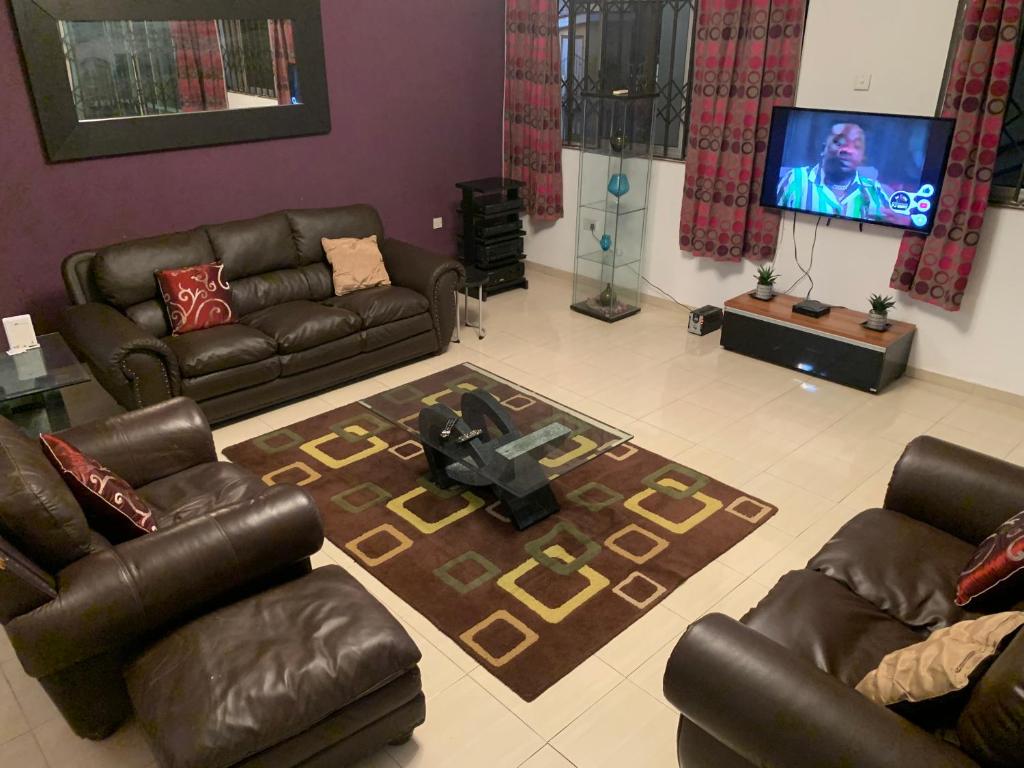 uma sala de estar com mobiliário de couro e uma televisão de ecrã plano em Accra Service villas - villa 2? em Spintex