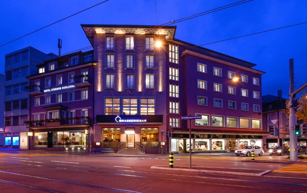 ein Gebäude an der Ecke einer Straße nachts in der Unterkunft Hotel Sternen Oerlikon in Zürich