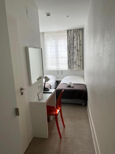 a small bedroom with a bed and a desk and a window at Residence OLit Cathédrale in Strasbourg