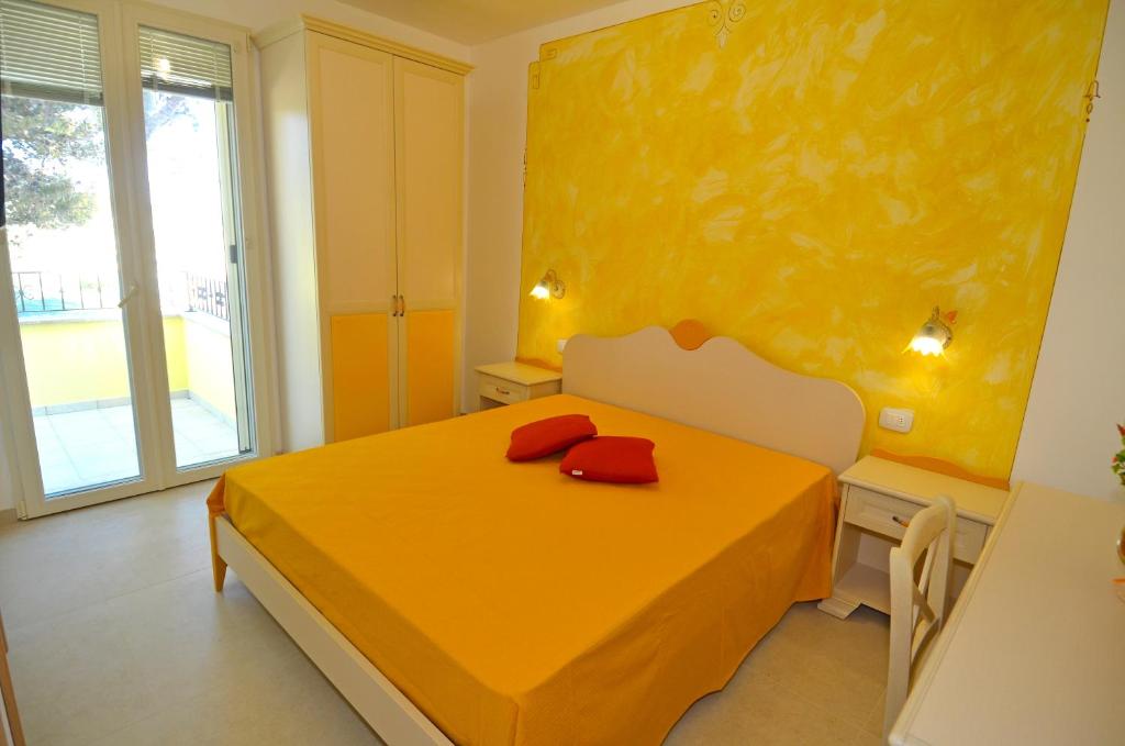 a yellow bedroom with a bed and a window at B&B Lu Cantoru in Marina di Pescoluse