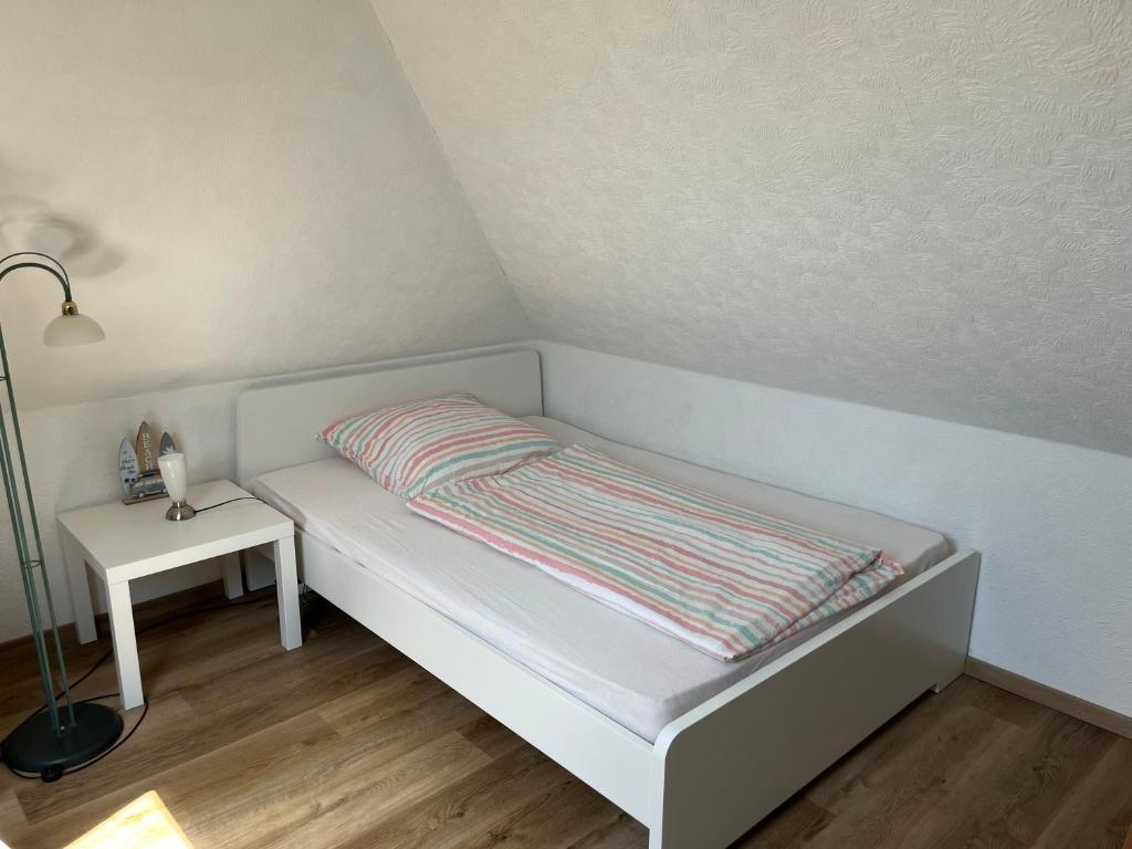 a small bed in a room with a lamp and a table at Apartment Topp adult only in Wangerland