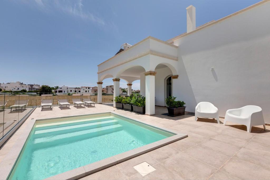 una piscina en un patio con sillas y una casa en Together In Salento, en Morciano di Leuca