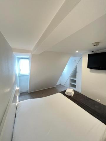a white room with a bed and a flat screen tv at Residence OLit Cathédrale in Strasbourg