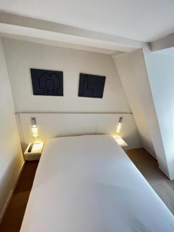 a white bed in a room with two pictures on the wall at Residence OLit Cathédrale in Strasbourg