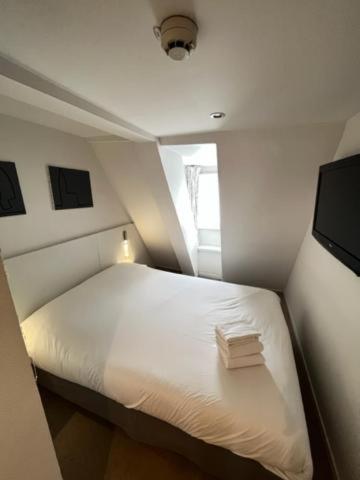 a small bedroom with a white bed and a television at Residence OLit Cathédrale in Strasbourg