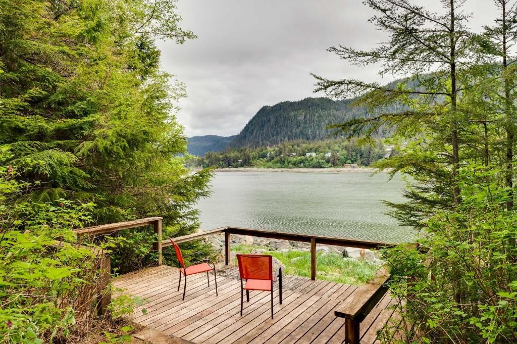 Mendenhaven的住宿－Juneau Vacation Home Stunning View and Beach Access，湖畔木甲板上配有两把椅子和一张桌子