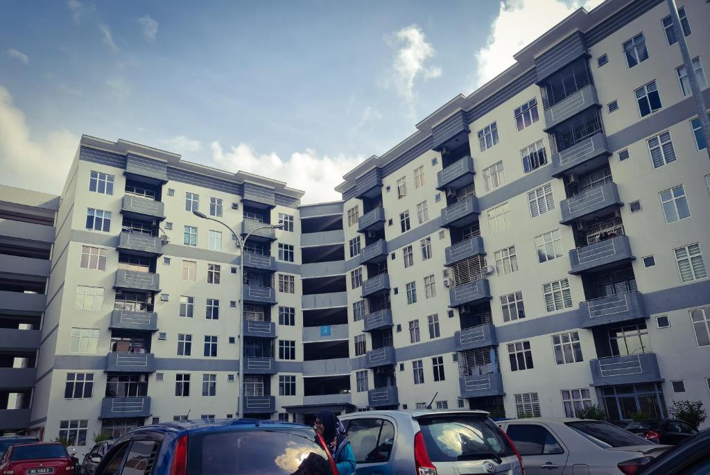 a parking lot with cars parked in front of tall buildings at JAZZ HOMESTAY JASIN BESTARI MELAKA in Kampong Bemban