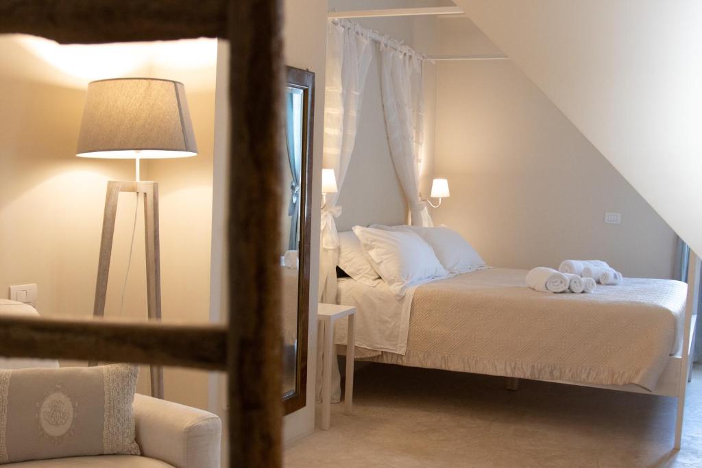 une chambre avec un lit avec des draps blancs et un miroir dans l'établissement Dimore Storiche Casalnuovo, à Conversano