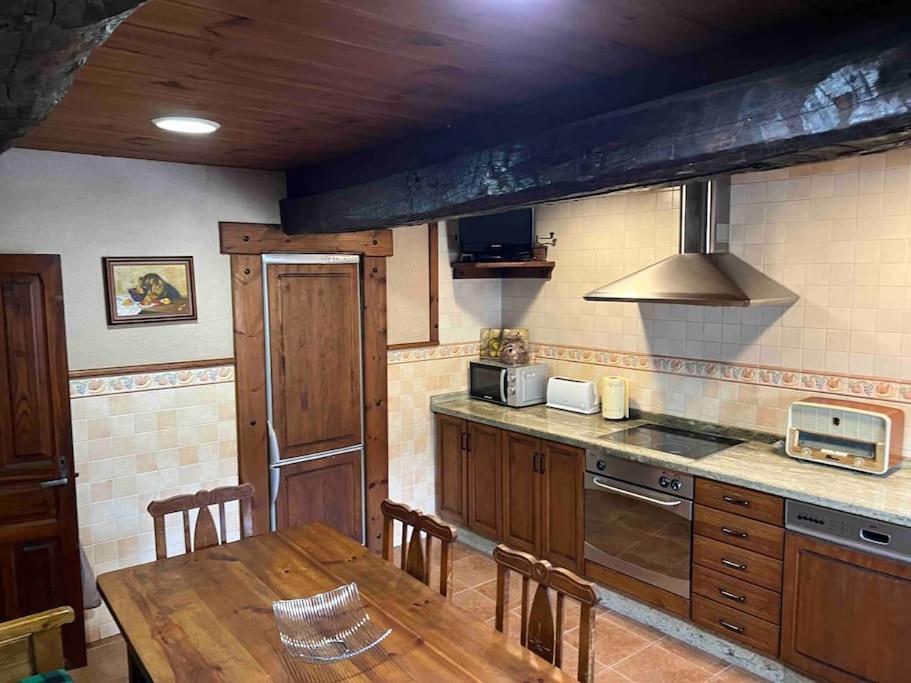 a kitchen with a wooden table and a table and chairs at Casa Lici in Robles de Laciana