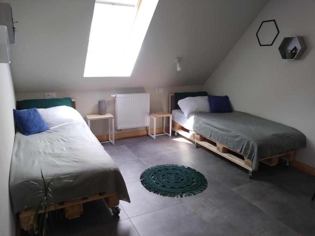a attic bedroom with two beds and a window at Apartamenty Zielone Drzwi in Kruklanki