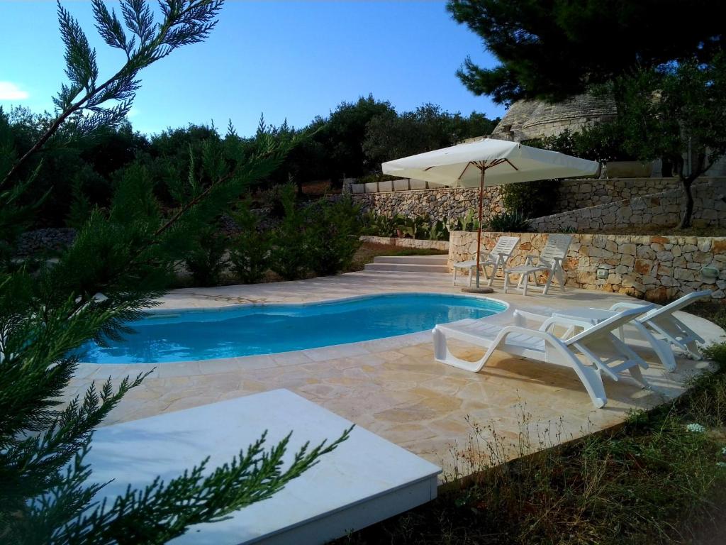a swimming pool with two chairs and an umbrella and an umbrella at Villa Trullo Panorama in Locorotondo