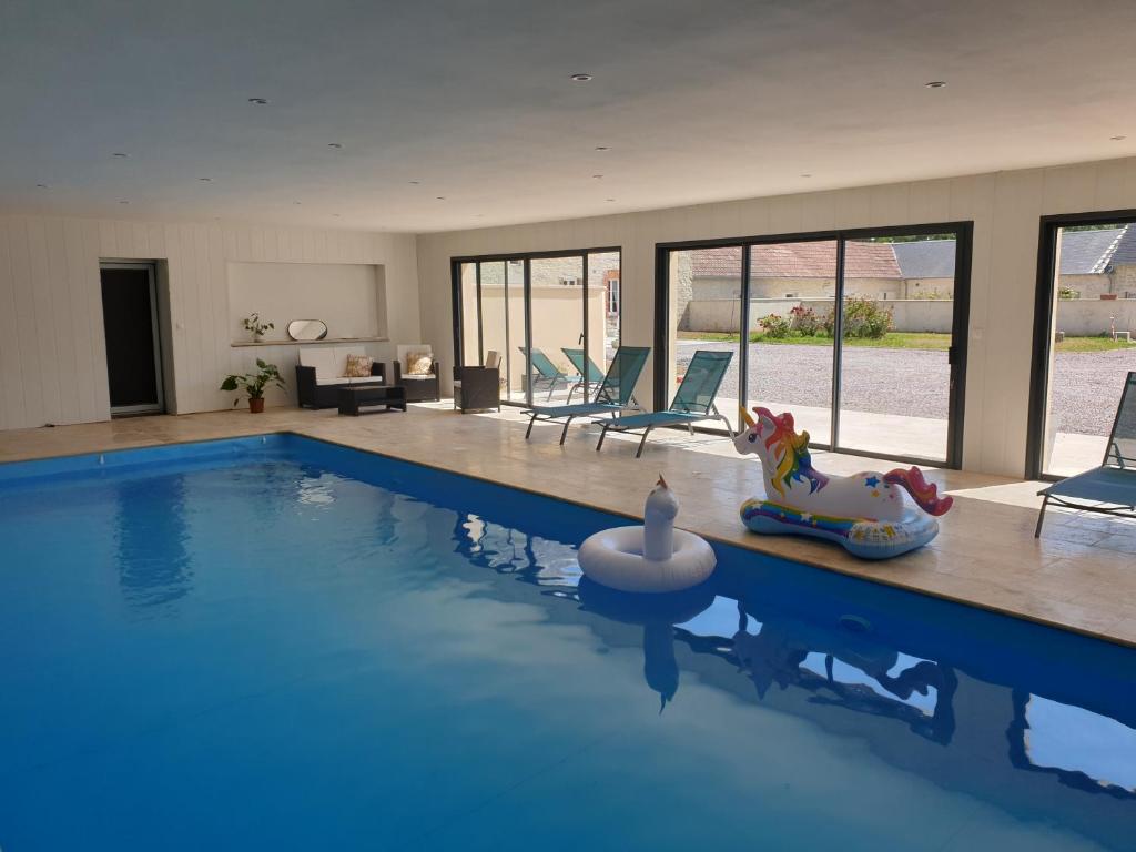 a swimming pool with a toy horse in a house at La Ferme de Barville & SPA in Écrammeville