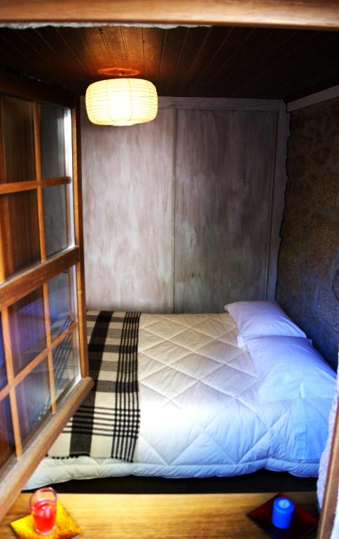 a bed in a small room with a window at Cantinho Santiago in Belmonte