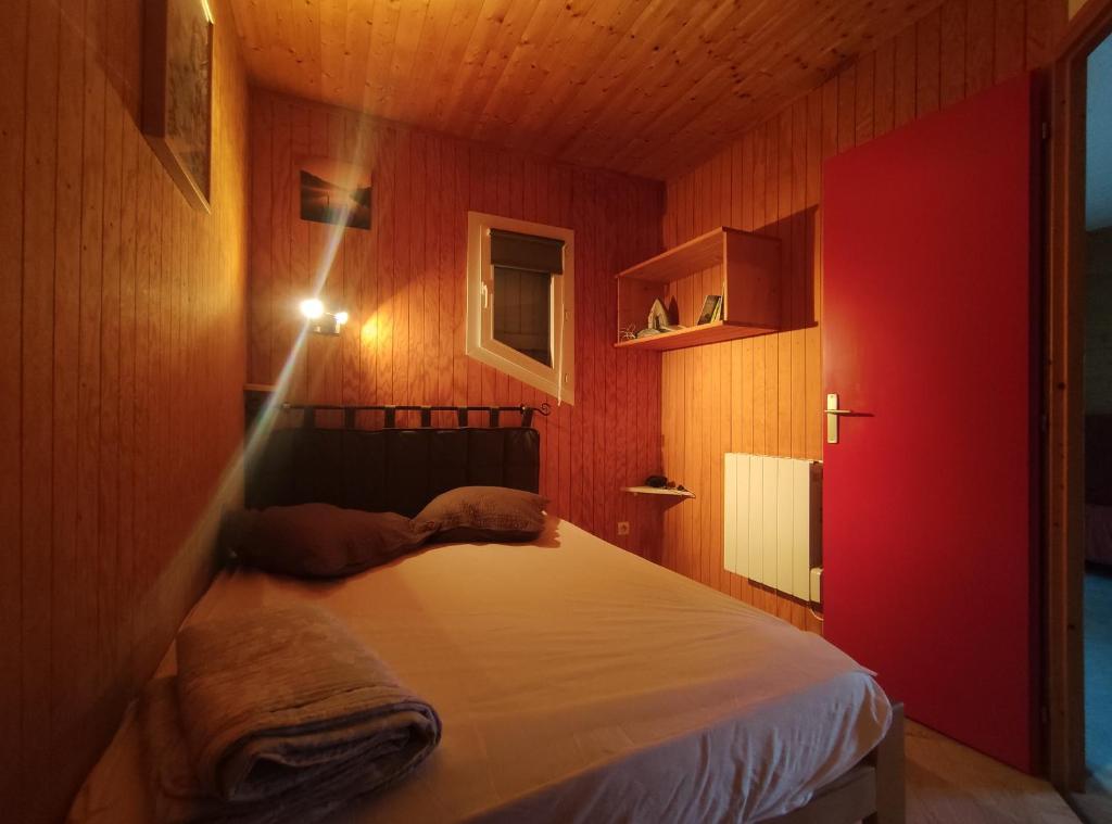 a bedroom with a bed with a red wall at Charmant chalet en Auvergne proche du lac in Saint-Rémy-sur-Durolle