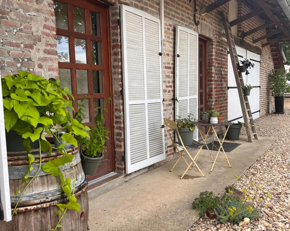 eine Terrasse mit Topfpflanzen und einer Tür in der Unterkunft Nature et calme in La Chapelle-Saint-Sauveur