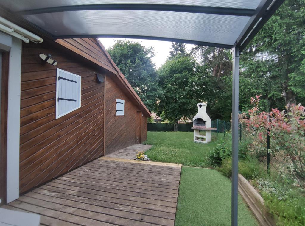 a pergola over a wooden walkway next to a house at Charmant chalet en Auvergne proche du lac in Saint-Rémy-sur-Durolle