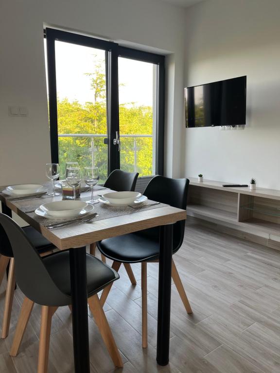 uma sala de jantar com uma mesa e cadeiras e uma televisão em Apartamenty Pod Jodłami em Sarbinowo