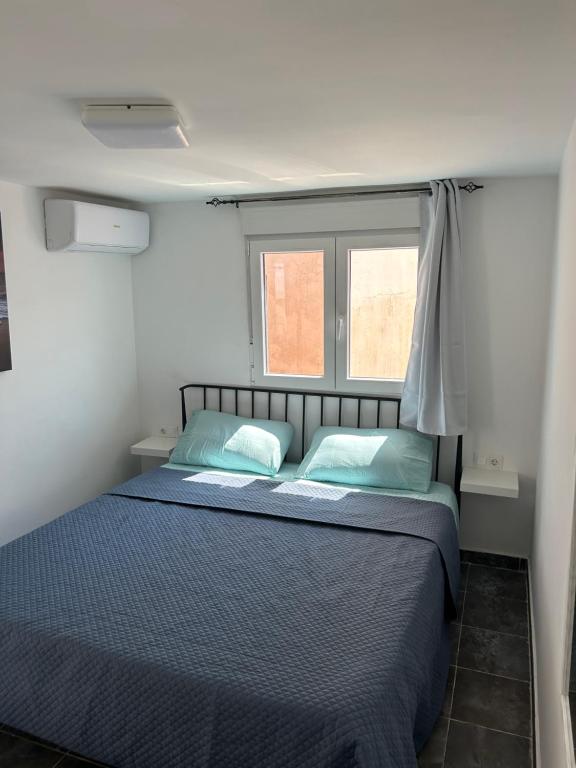 - une chambre avec un lit doté de draps bleus et 2 fenêtres dans l'établissement Casa Manoli, à Torremolinos