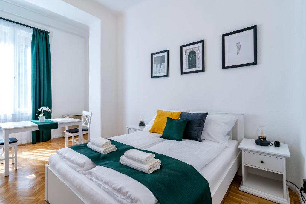 a white bedroom with a large bed and a table at Budafoki Residence in Budapest