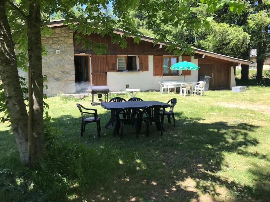 a table with chairs and an umbrella in a yard at Chalet rouge gorge in Mars