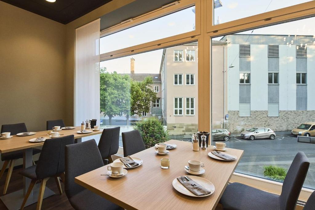a meeting room with tables and chairs and a large window at Hotel Rhönkitz in Bad Kissingen