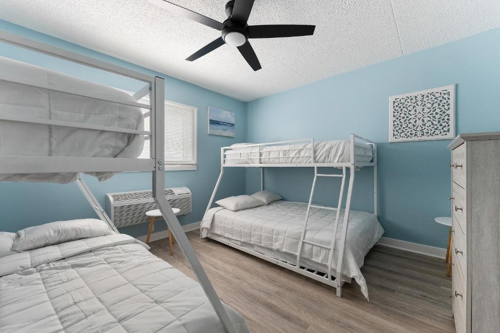 a bedroom with two bunk beds and a ceiling fan at Harbor Light Family Resort in North Wildwood