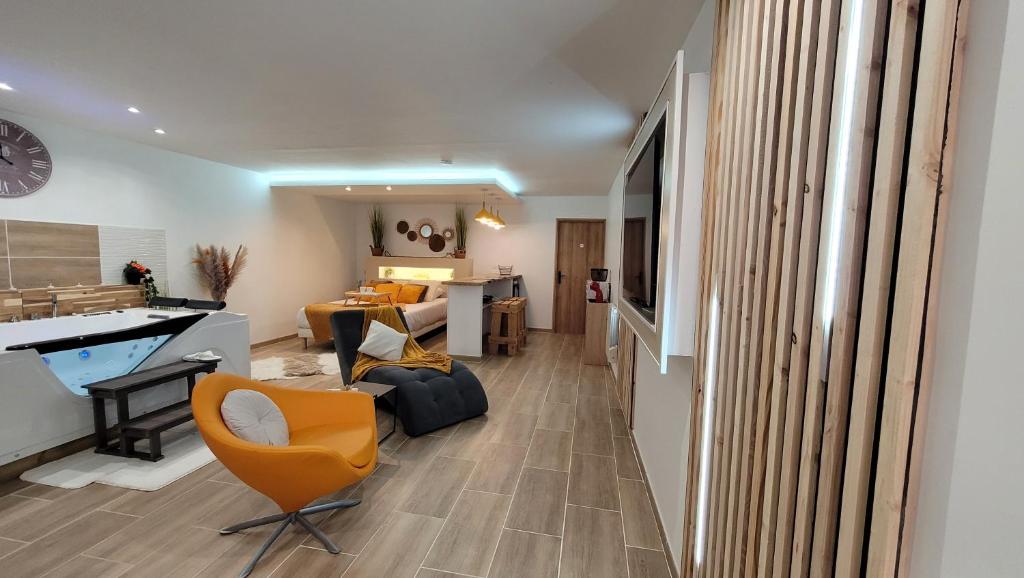 sala de estar con silla naranja y sofá en Grand Studio magnifique avec Spa privatif illimité, en La Bassée