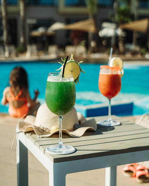 two cocktails sitting on a table next to a pool at Waves Aqua Resort in Kenitra