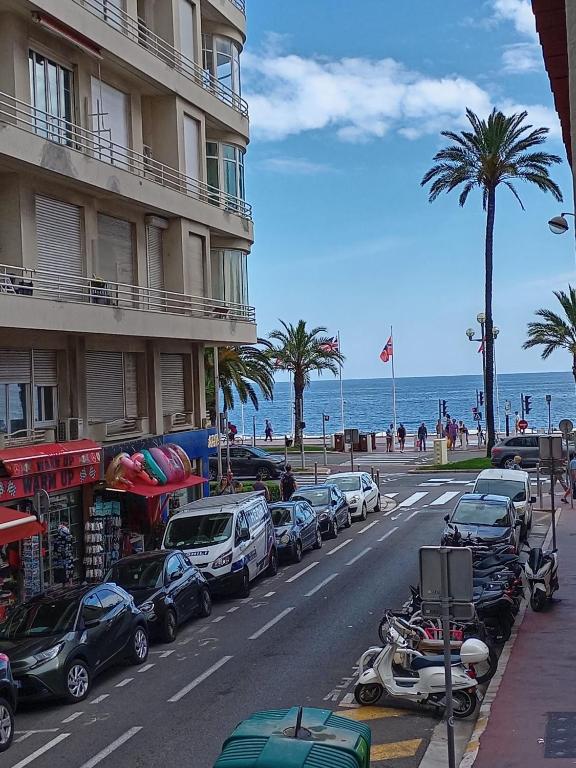 une rue avec une rangée de voitures garées à côté de la plage dans l'établissement Meyerbeer YourHostHelper, à Nice