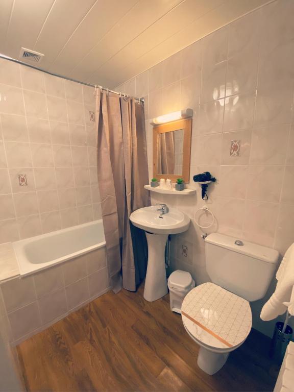 a bathroom with a sink and a toilet and a tub at Hôtel Restaurant "La Petite Auberge" in Bourg-Saint-Maurice