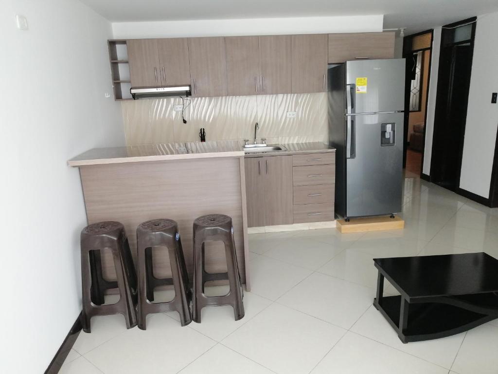 a kitchen with a counter and stools and a refrigerator at Moderno apartamento para huespedes in Ipiales