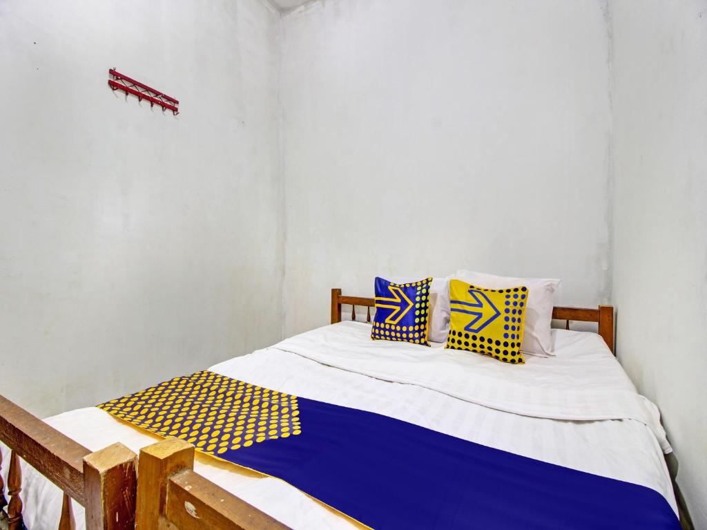 Schlafzimmer mit einem Bett mit blauen und gelben Kissen in der Unterkunft SPOT ON 92539 Luqman Kostel Syariah in Semarang