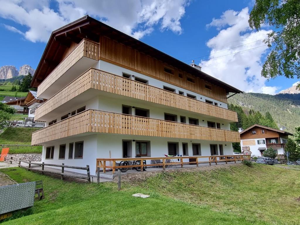 a building with a balcony on top of a field at Stella Alpina in Campitello di Fassa
